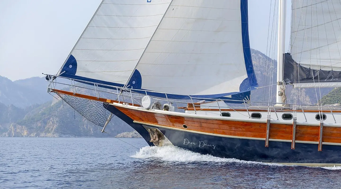 Diva Deniz yacht with wooden hull gliding on blue water at sunset
