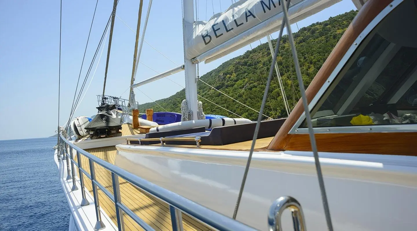Bella Mare yacht with blue hull, moored at sunset on calm coast