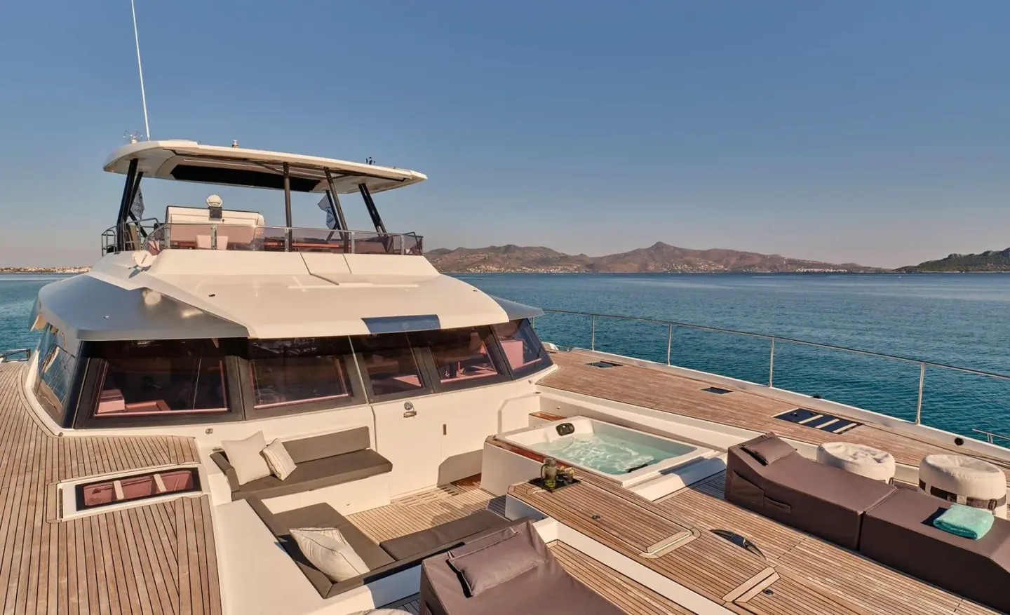 Bow deck of Christal Mio yacht with sun loungers and blue sea