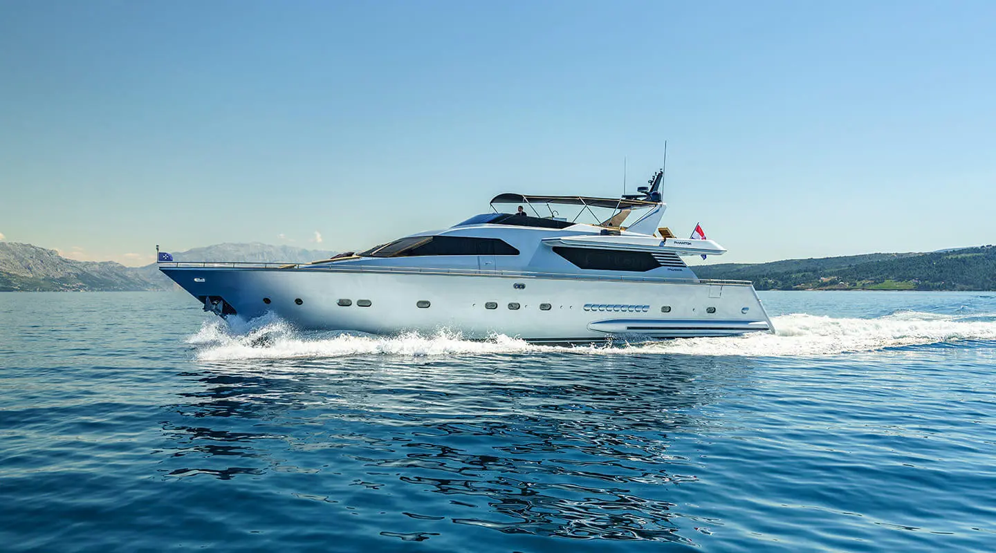 Phantom motor yacht cruises on calm blue sea, white hull cutting through water