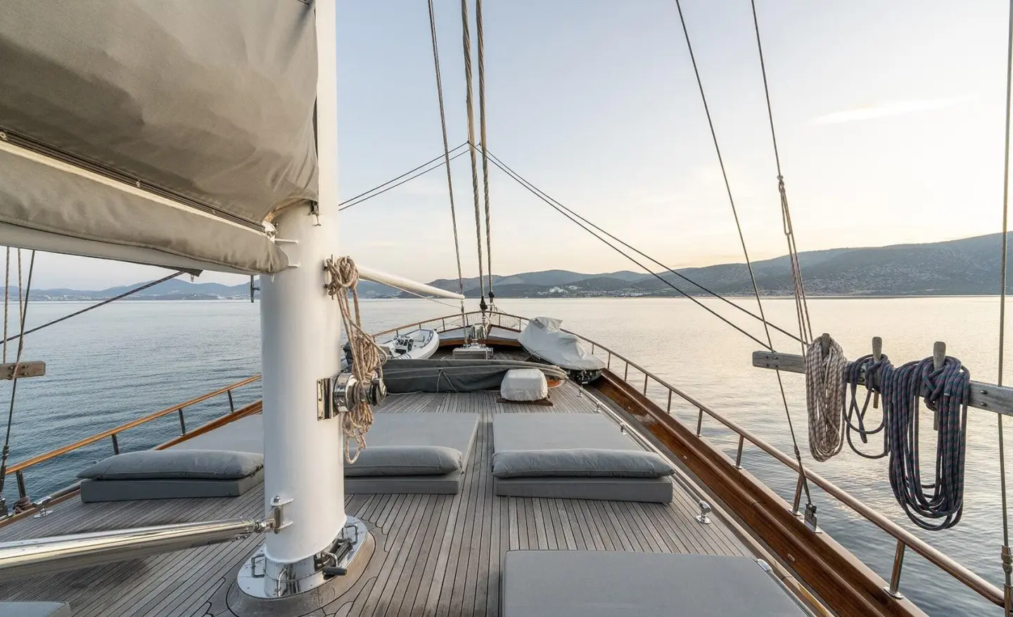 Sunset on a yacht deck with ropes, railing, and calm sea in view