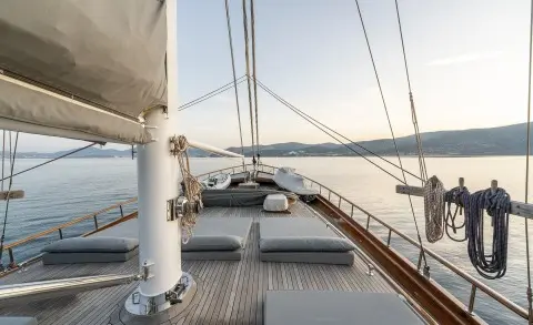 Sunset on a yacht deck with ropes, railing, and calm sea in view