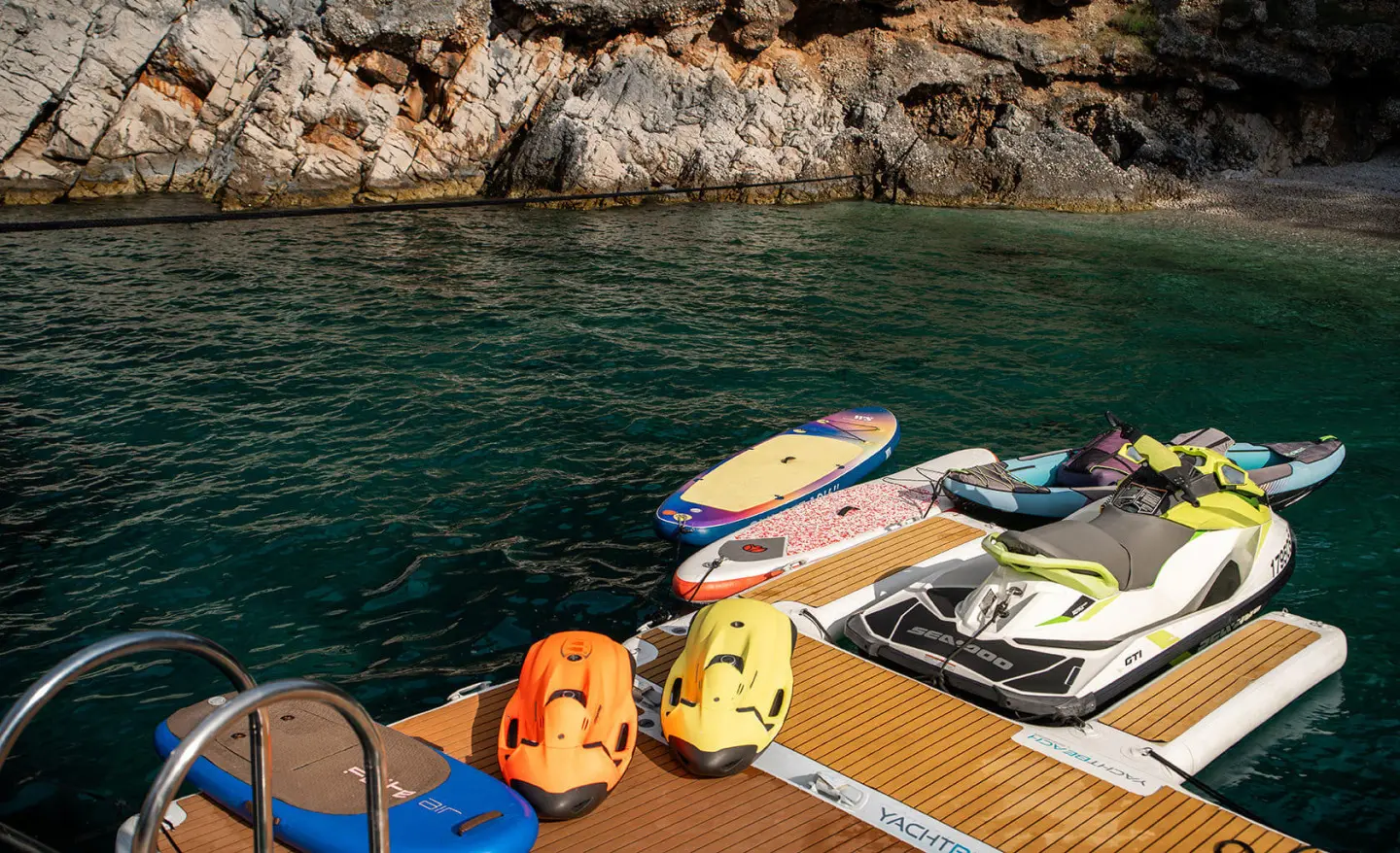 Dalmatino yacht docked in turquoise water with colorful inflatable toys on the jetty