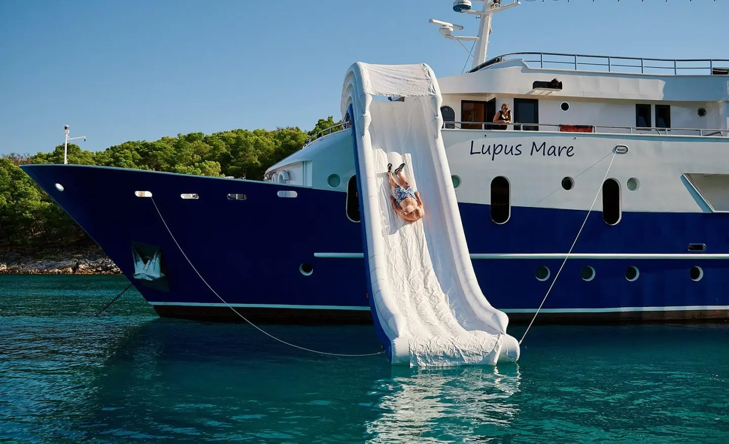 Lupus Mare yacht moored near a small white slide descending into turquoise water