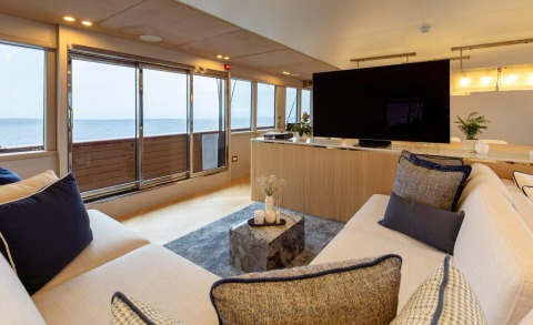 Scorpios luxury yacht interior: spacious lounge with sea view, cream sofa, navy cushions, marble coffee table