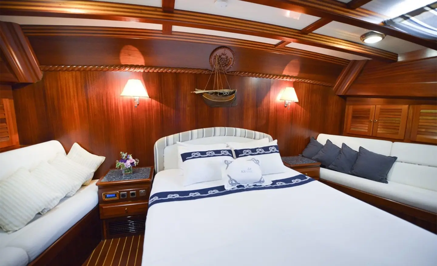Wood-paneled cabin with bed and throw pillows, bedside tables