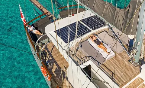 A luxury gulet yacht Virtuoso docked at sunset with wooden deck and sails