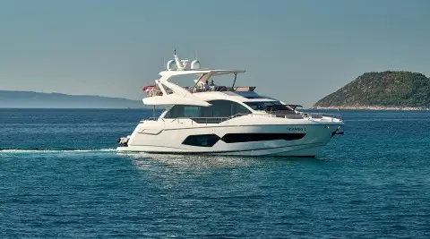 White luxury yacht Hideaway I glides on calm blue waters near a rocky coastline
