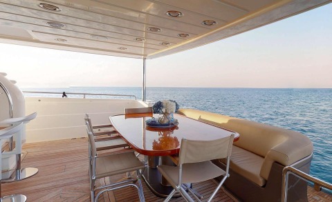 Lady Natassa yacht deck with dining table and chairs overlooking the sea at sunset