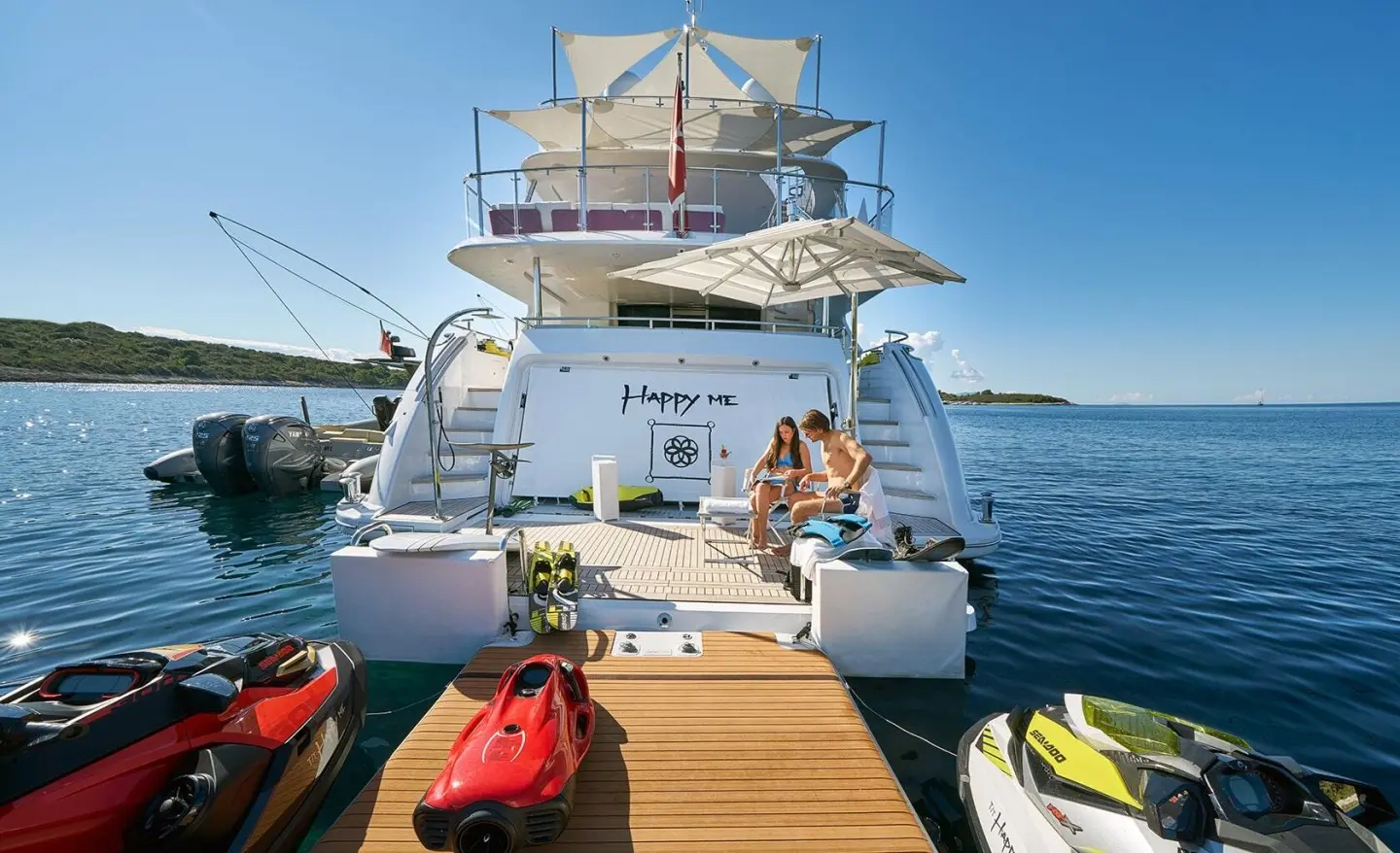 Happy Me yacht docked with people on a wooden pier and small boats nearby
