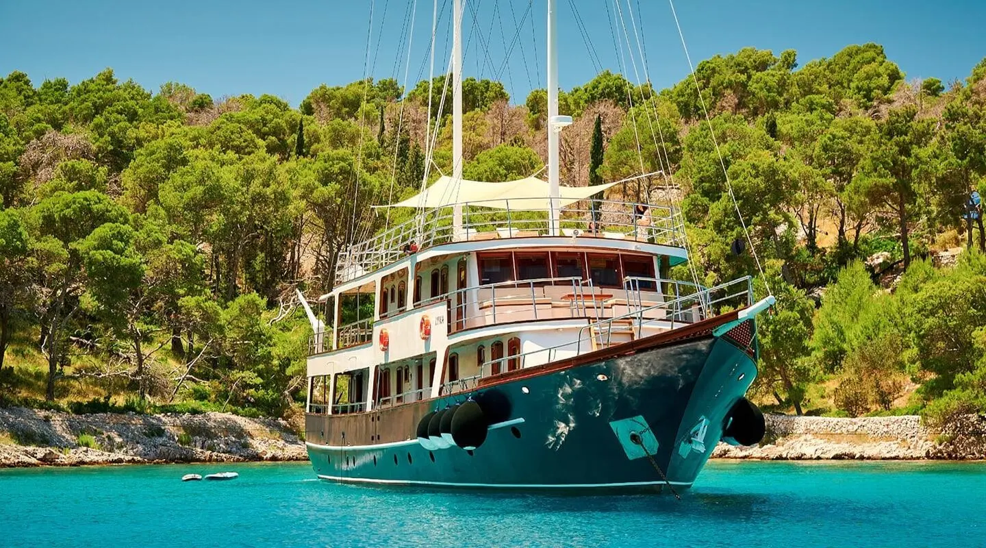 Luna yacht anchored near rocky shore with palm trees and clear blue water