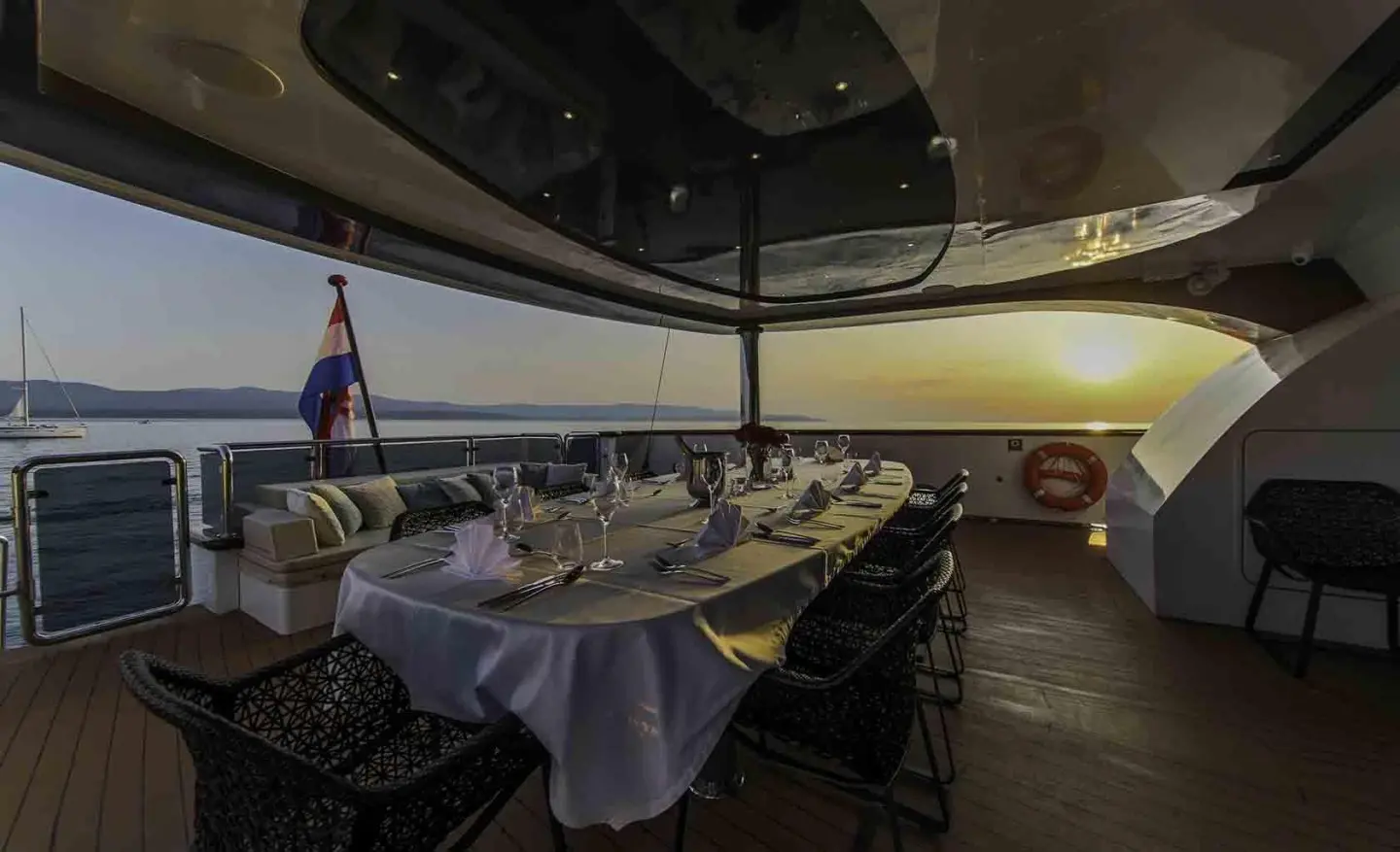 Omnia yacht dining outdoors at sunset with table setup and sea view