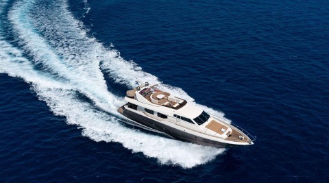 White and brown luxury motor yacht cruising at speed on deep blue sea