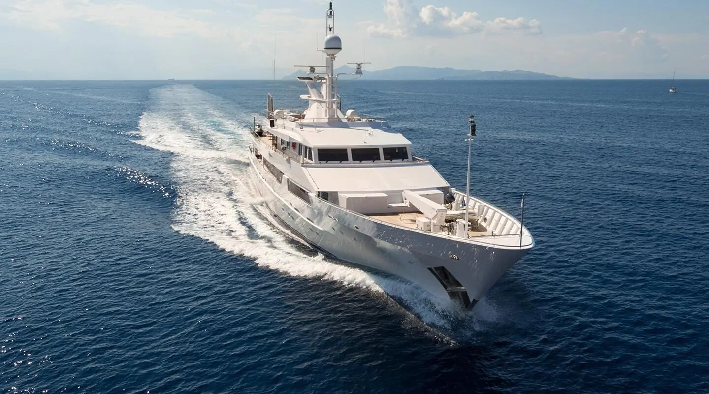 A luxurious white yacht named O'Natalina sails on calm blue sea, wake visible