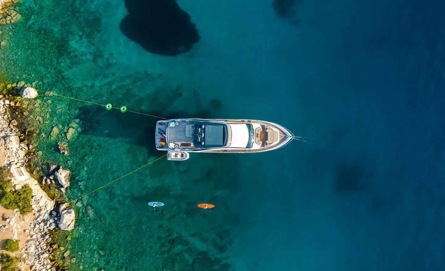 Aerial view of a white motor yacht named Vista anchored in clear blue water