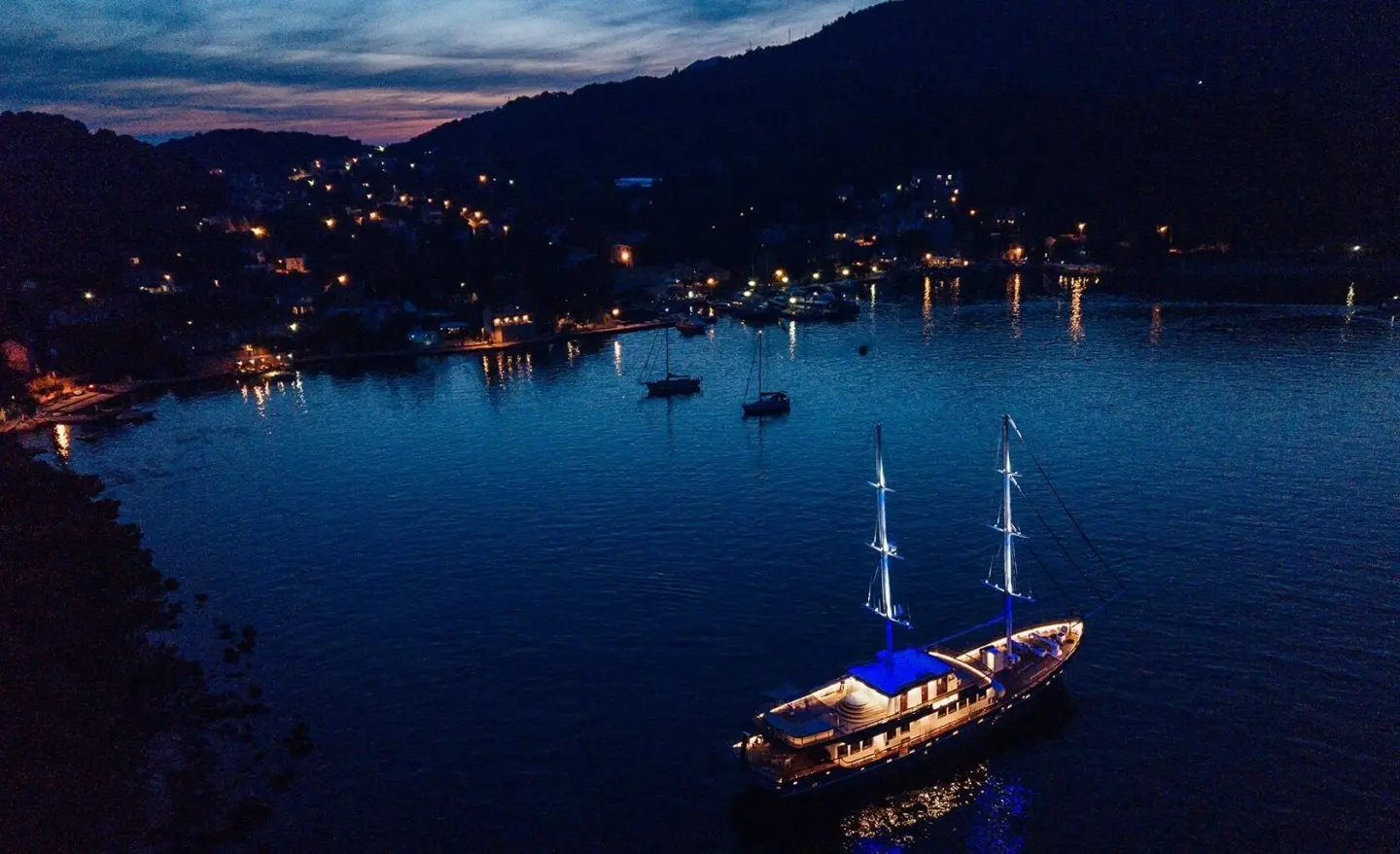 Gulet Corsario anchored at night with lights reflecting on calm water