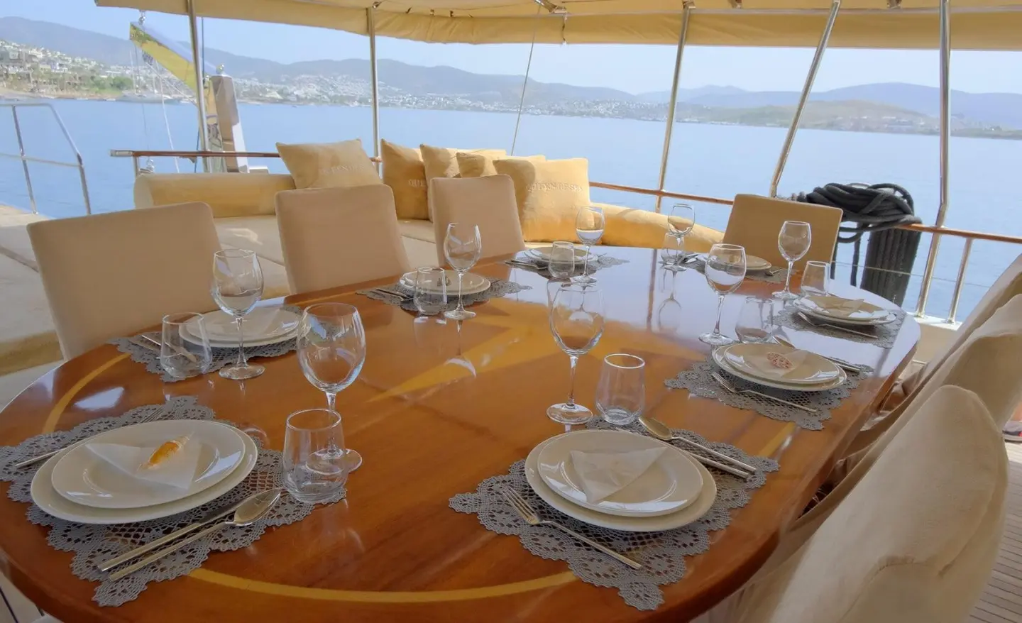 Queen Of Sea yacht deck set for sunset dining with plates and chairs