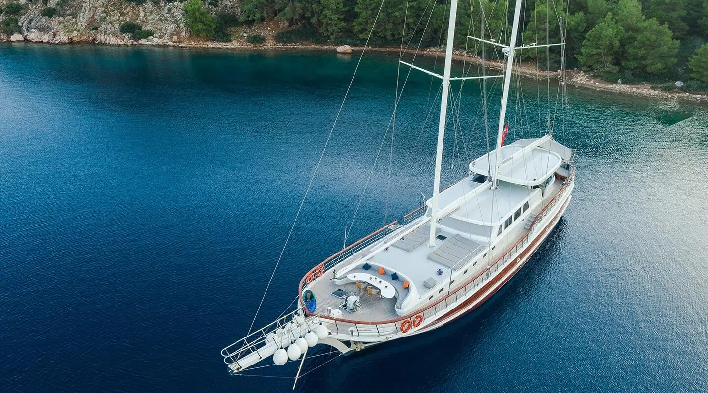 Vista Mare yacht anchored near a rocky shoreline with clear blue water