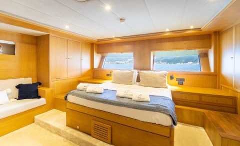 Gulet Happy Days master cabin interior with wooden panels and bed near windows