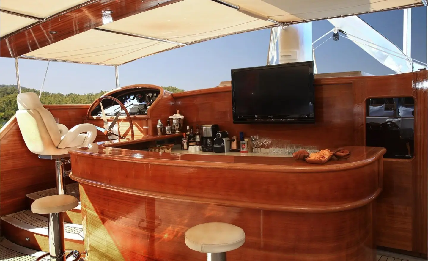 Kaya Guneri 5 yacht bar area with wooden deck, seating, and sunset backdrop