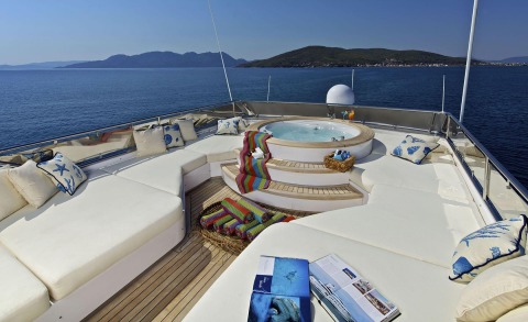 O'Rion yacht deck: circular spa tub, cream loungers, colorful towels, and ocean view