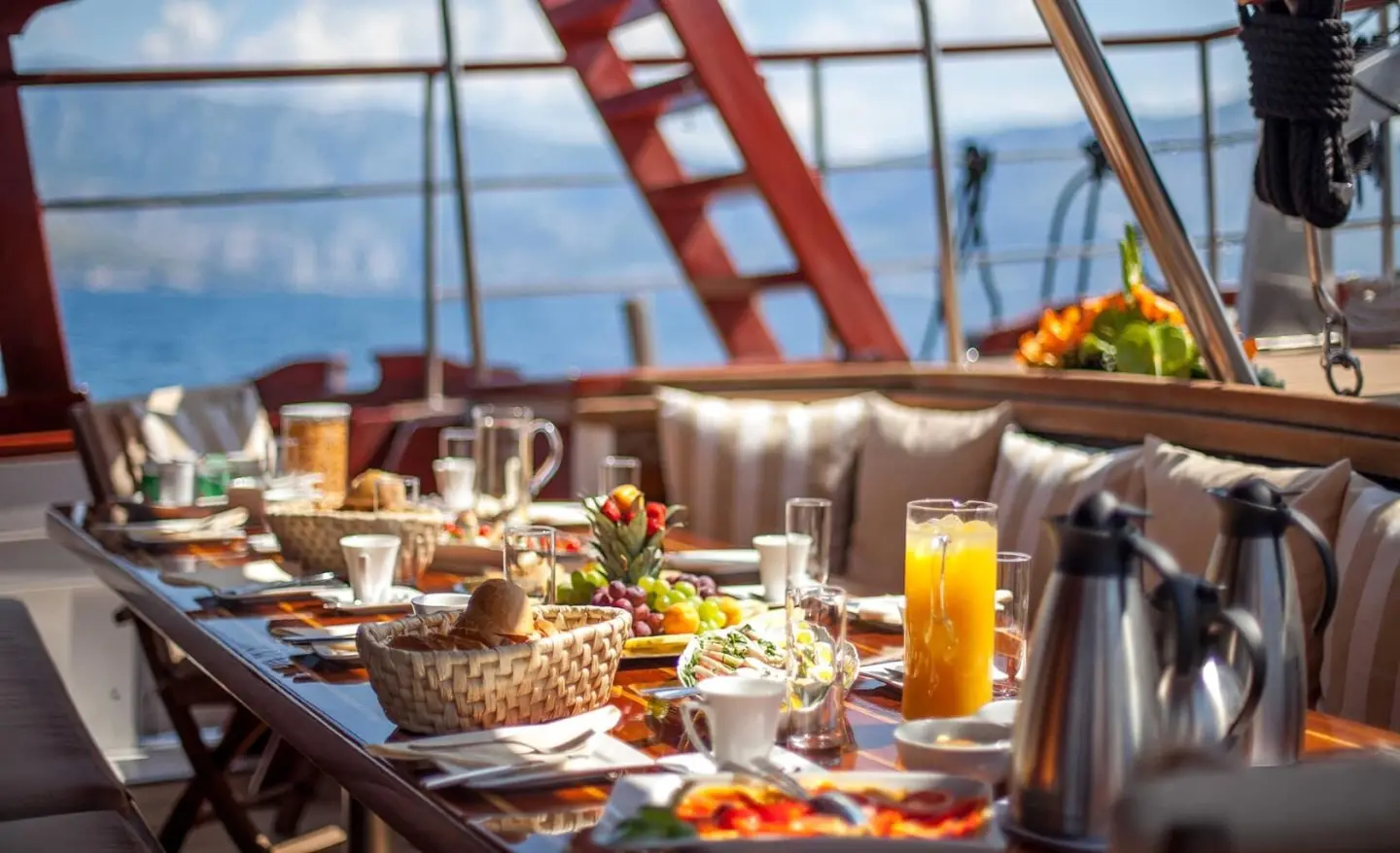 Romanca yacht dining setup on deck with sunset sea view and table sunlight
