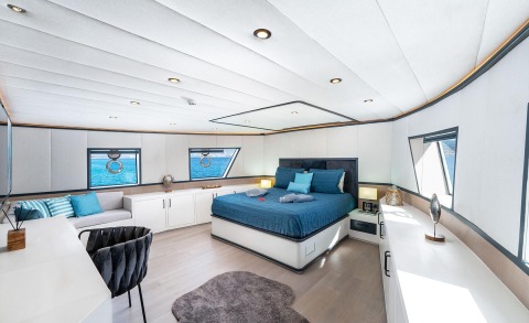 Interior of a bedroom with a large bed in blue bedding and white furniture