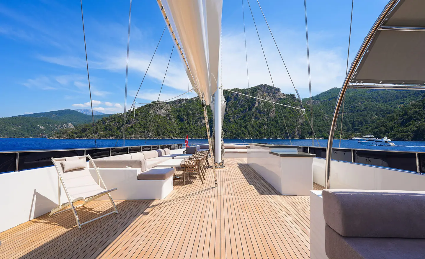 View from yacht deck toward sunset, ropes, sails, and calm blue sea
