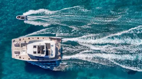 Christal Mio yacht cruising at sunset with wake patterns in turquoise sea