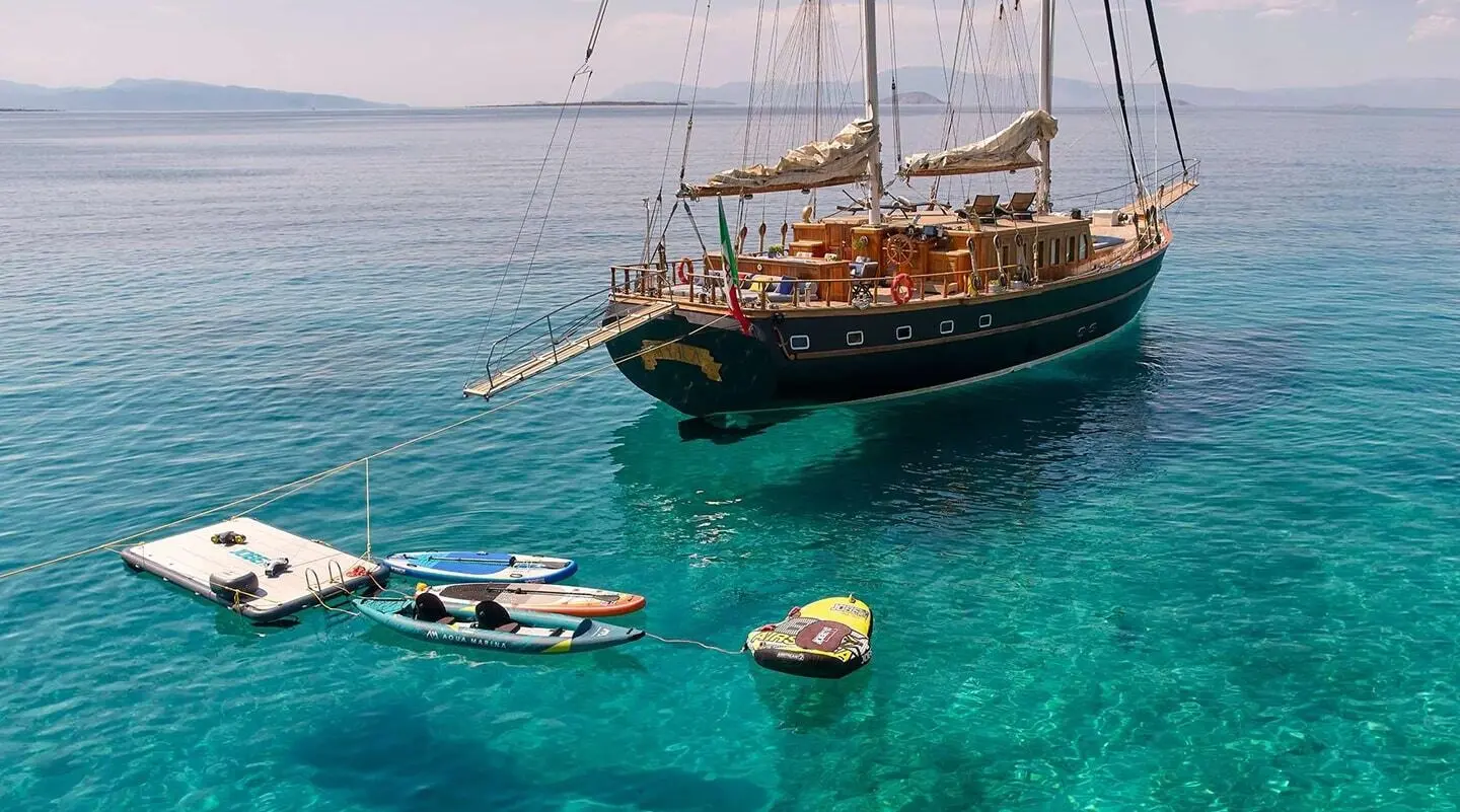 Myra yacht anchored near turquoise sea with a dinghy and small boat nearby