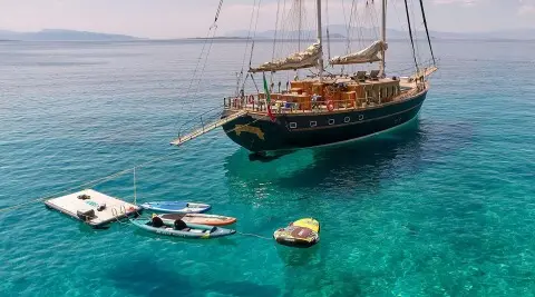 Myra yacht anchored near turquoise sea with a dinghy and small boat nearby