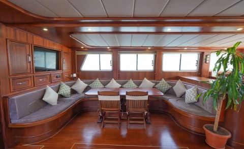 Prenses Esila interior: mahogany wood salon with curved sofa seating and dining table