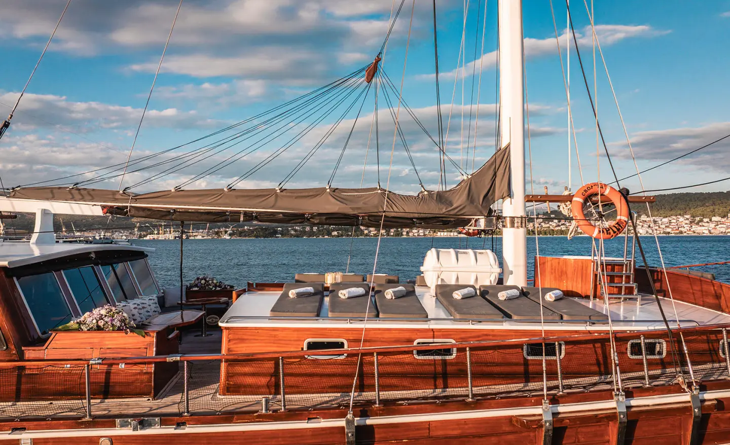 Boat deck with wooden railings and sails, Croatia yacht at sea under blue sky