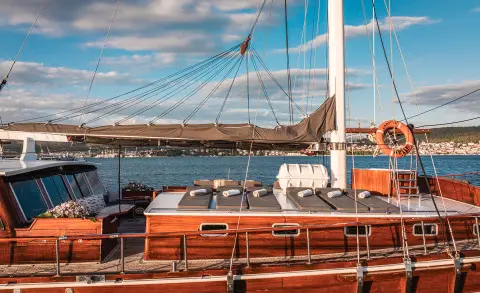 Boat deck with wooden railings and sails, Croatia yacht at sea under blue sky