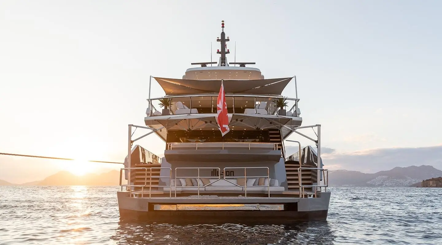 Illusion II yacht at sunset with multiple decks, stern view, water behind