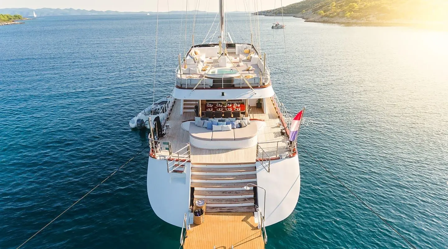 A luxurious motor yacht named Lady Gita docked with a wooden gangway to shore, sunset lighting