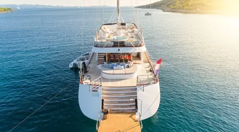 A luxurious motor yacht named Lady Gita docked with a wooden gangway to shore, sunset lighting