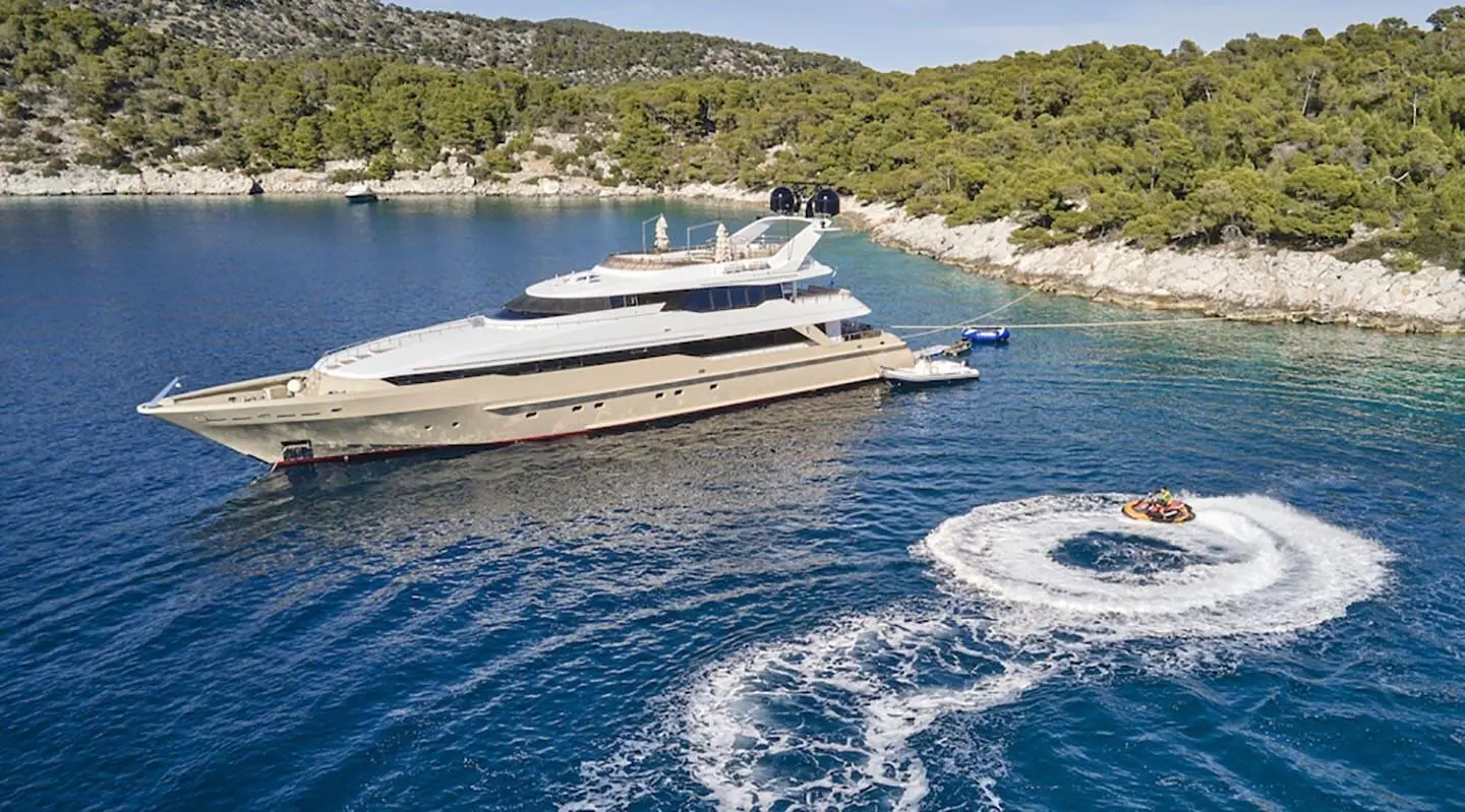 Daloli luxury yacht anchored by rocky green shoreline in blue sea