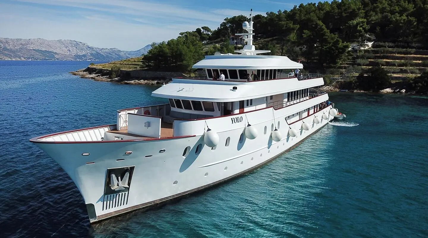 Yolo luxury yacht anchored by rocky shore with clear blue water