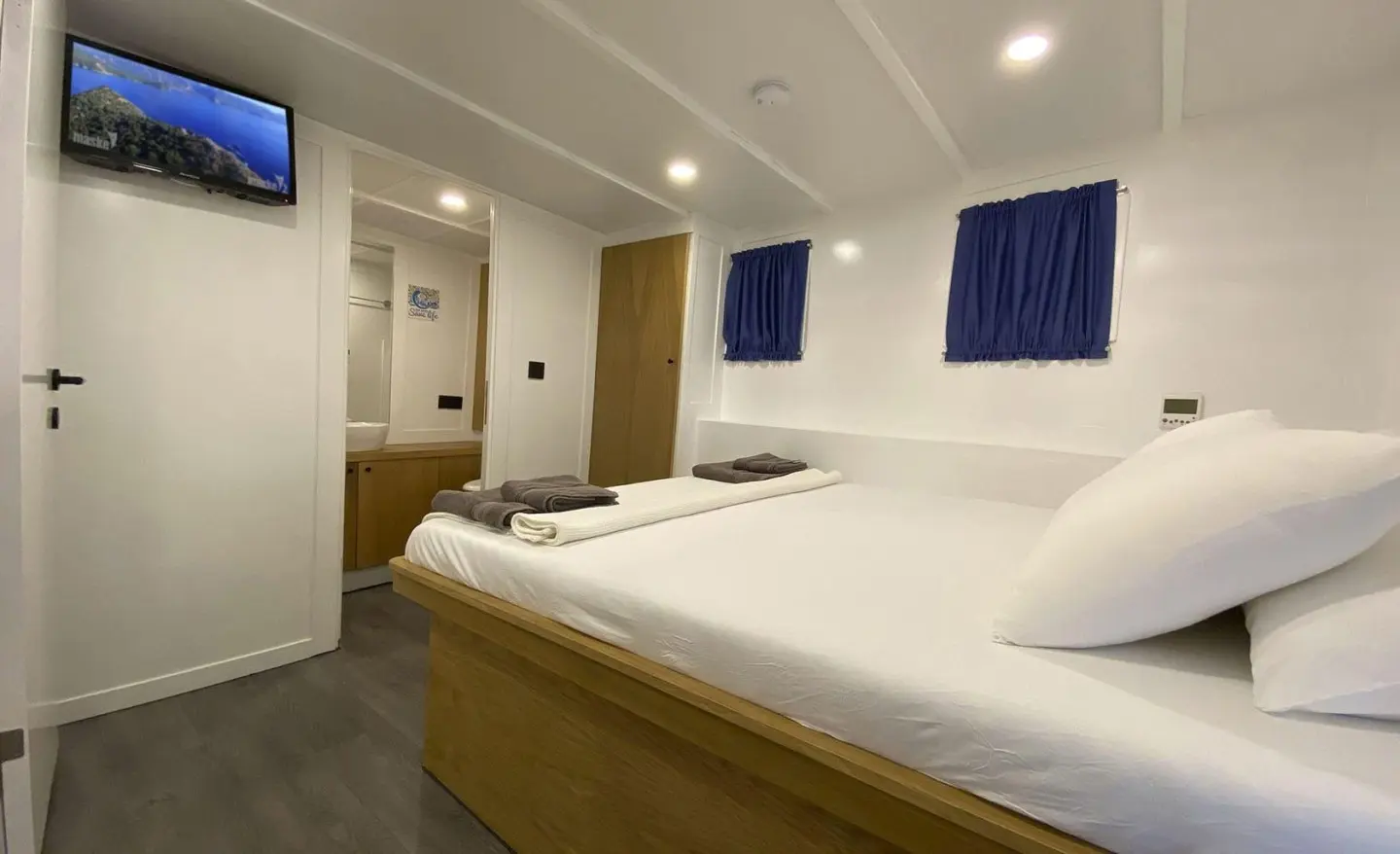 Maske 5 gulet interior with a double bed and blue curtains