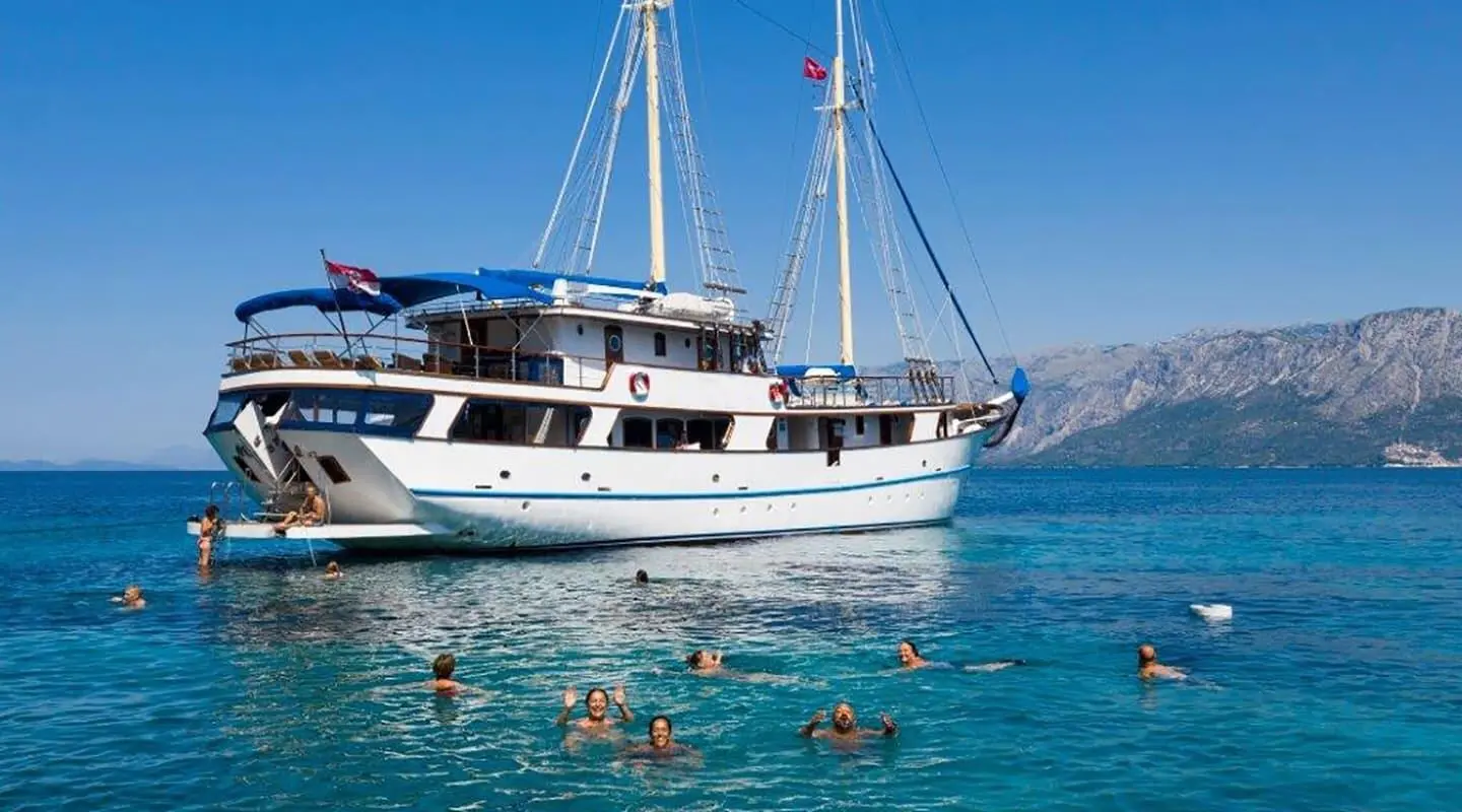Mendula yacht with white hull and masts anchored in clear blue water