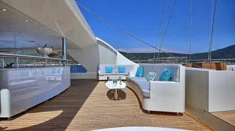 Meira yacht deck seating area with white cushioned benches and circular table