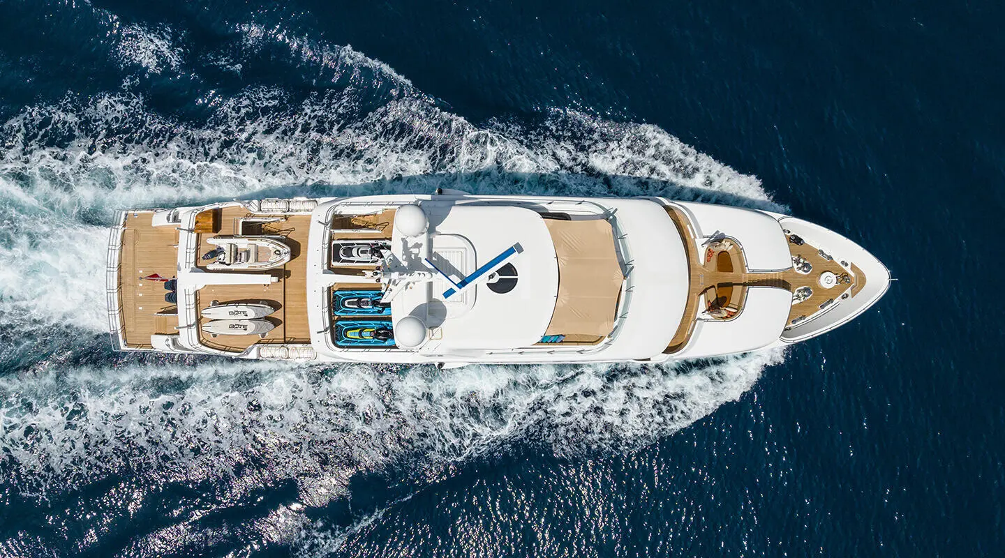 Aerial view of Serenity luxury yacht cutting through blue sea, wake visible