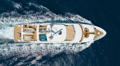 Aerial view of Serenity luxury yacht cutting through blue sea, wake visible