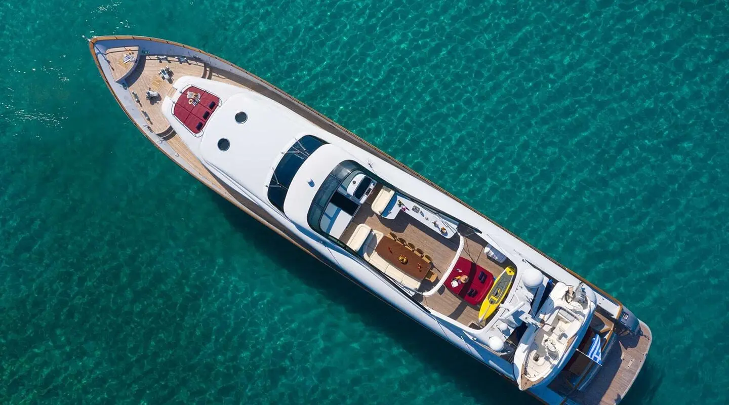 Aerial view of a white motor yacht named Glaros cruising turquoise open water