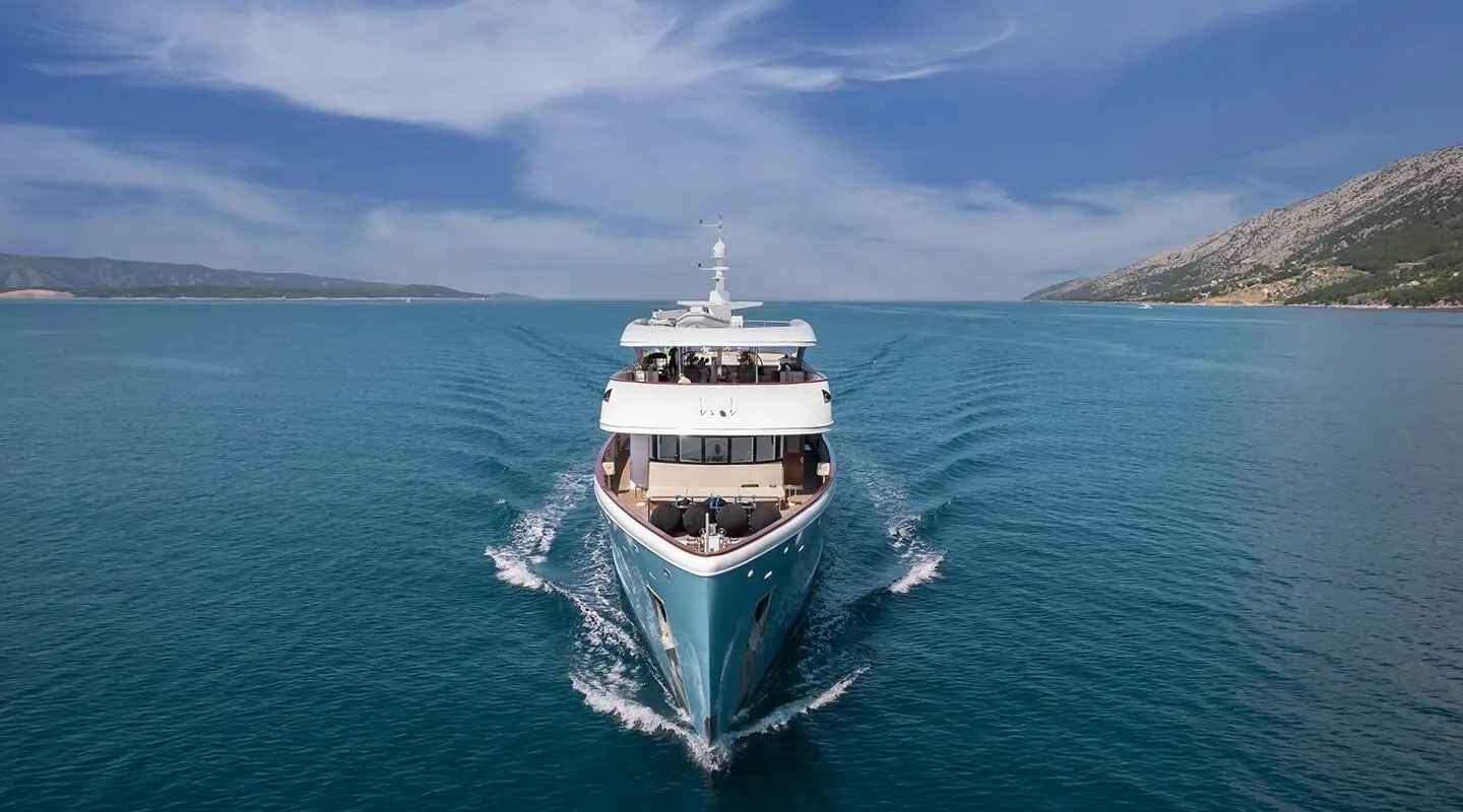 Ohana motor yacht cruising toward viewer in blue sea, clear sky, wharfless horizon