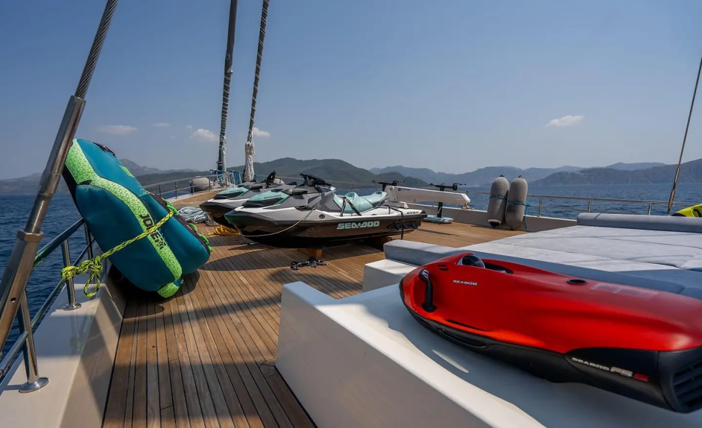 Deck of luxury yacht De Love with colorful inflatable floatation toys and calm harbor view