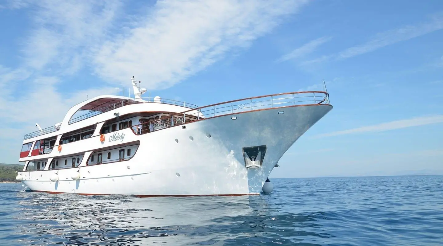 Melody yacht in white cruising on open sea, side view with bow