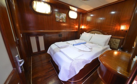 Luxurious yacht cabin interior with wooden panels, bed and white linens
