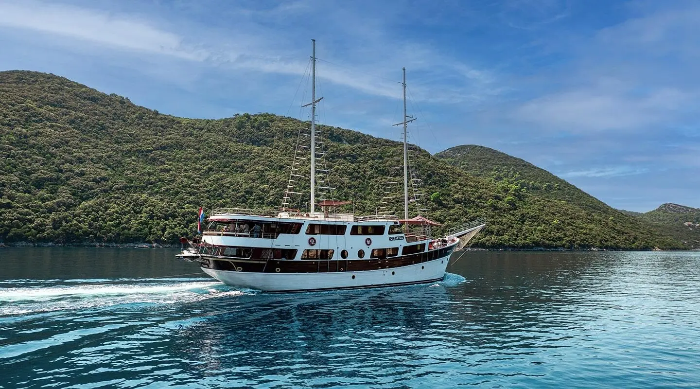 Cesarica luxury sailing yacht cruising calm turquoise waters near green island hills